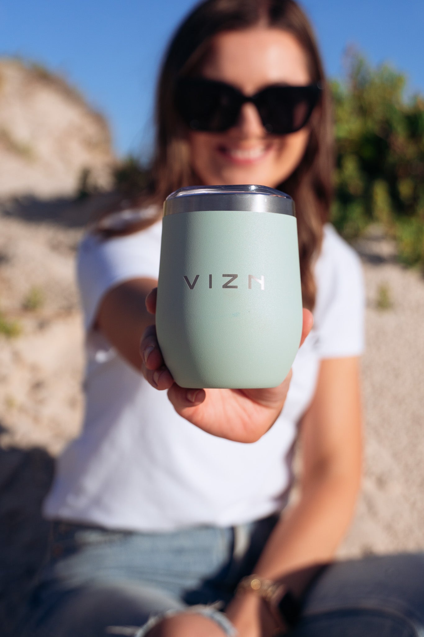 Seam Foam Green Sipper Tumbler with a close-up view of its sleek stainless steel finish being used outdoors.