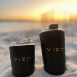Big and small reusable stainless steel coffee cups in the sand.
